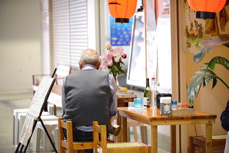 のうれんプラザ｜店先のテーブルに座る男性の後ろ姿