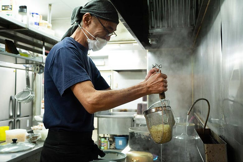 古謝そば屋|麺の湯切りをする男性
